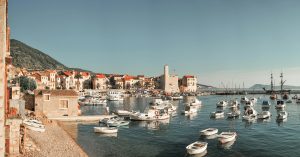 A picturesque view of Komiža harbor in Croatia with boats, historic buildings, and calm sea.