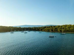 Calm waters with sailboats anchored near Vrboska, Croatia, under a clear sky.